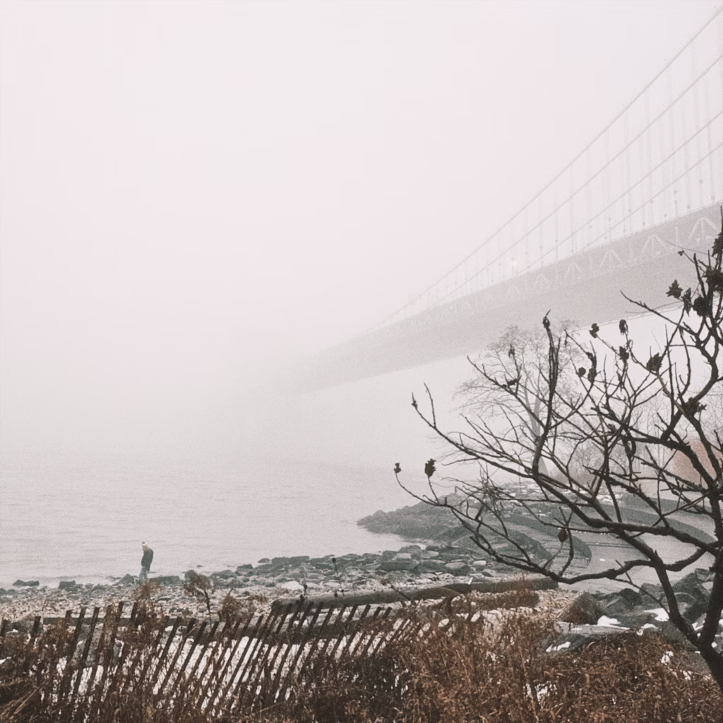 A foggy photo of the brooklyn bridge taken from pebble beach.